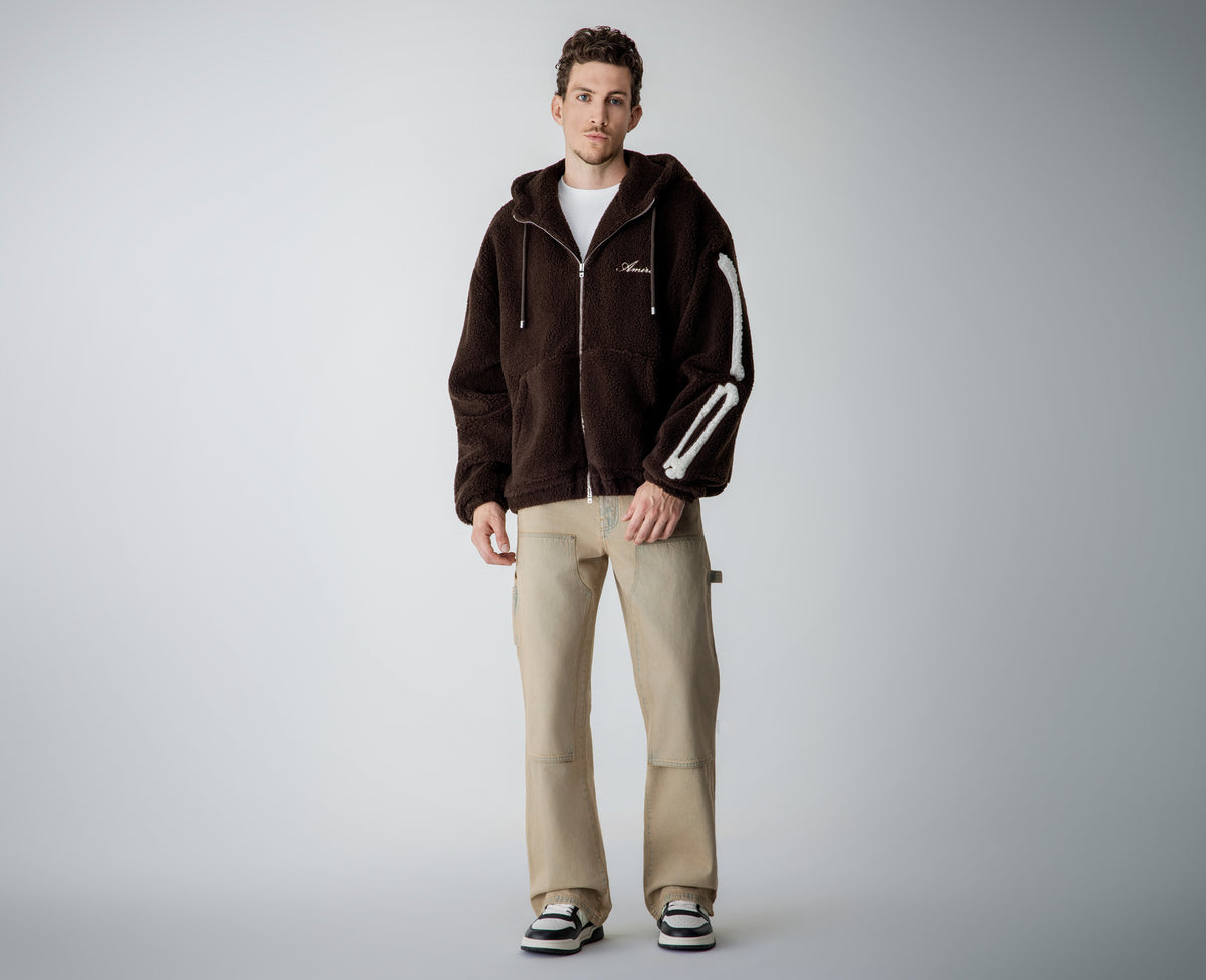 Menswear new arrivals: man in a brown fleece zip-up hoodie and beige carpenter jeans